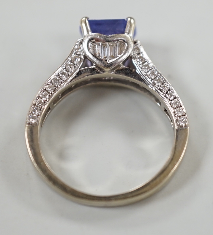 A modern 18ct gold and single stone emerald cut tanzanite set dress ring, with graduated baguette and round cut diamond set shoulders and graduated baguette cut diamond set heart shaped setting, size I, gross weight 4.7